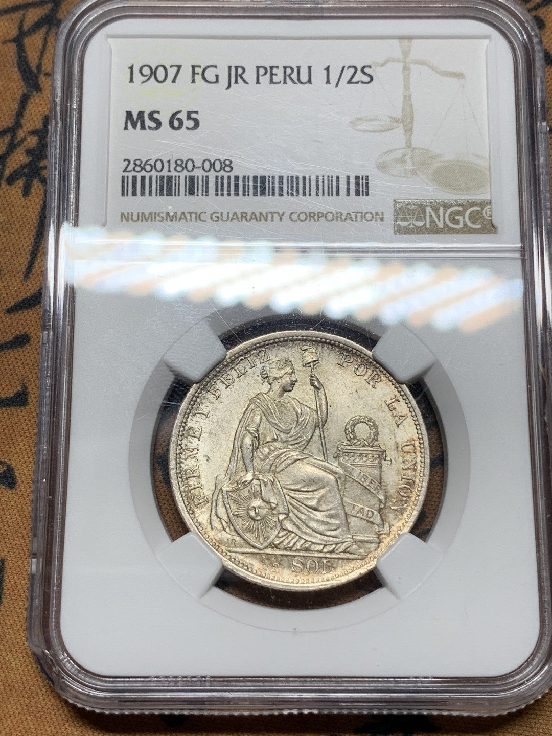 《竞宝斋》钱币微拍-第25场-本周日，周一2场连拍（全场顺丰包邮） ngc-ms65 1907年秘鲁半索尔坐洋女神 包浆好 状态佳 少见稀有特年 sbp落槌价240刀 盒子左下角有磕