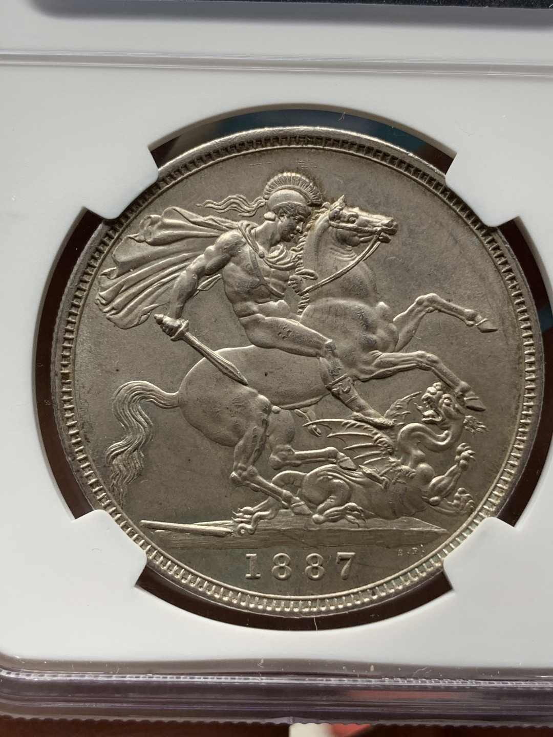 《竞宝斋》钱币微拍-第25场-本周日，周一2场连拍（全场顺丰包邮） NGC MS64 英国1887年维多利亚女王高冠马剑1克朗银币 淡彩包浆 状态一流