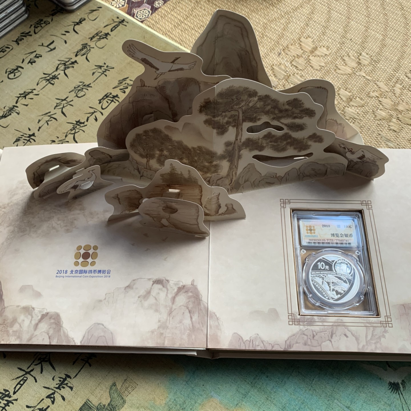 《竞宝斋》第38场-本周一 （全场顺丰包邮） (纪念银币+护照，全套)2018年 北京国际币展现场纪念册 纪念银币1枚 护照一本 邮戳齐 带荧光戳 封面为一枚生肖银章 