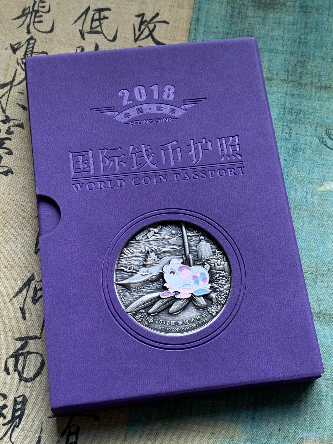 《竞宝斋》第38场-本周一 （全场顺丰包邮） (纪念银币+护照，全套)2018年 北京国际币展现场纪念册 纪念银币1枚 护照一本 邮戳齐 带荧光戳 封面为一枚生肖银章 