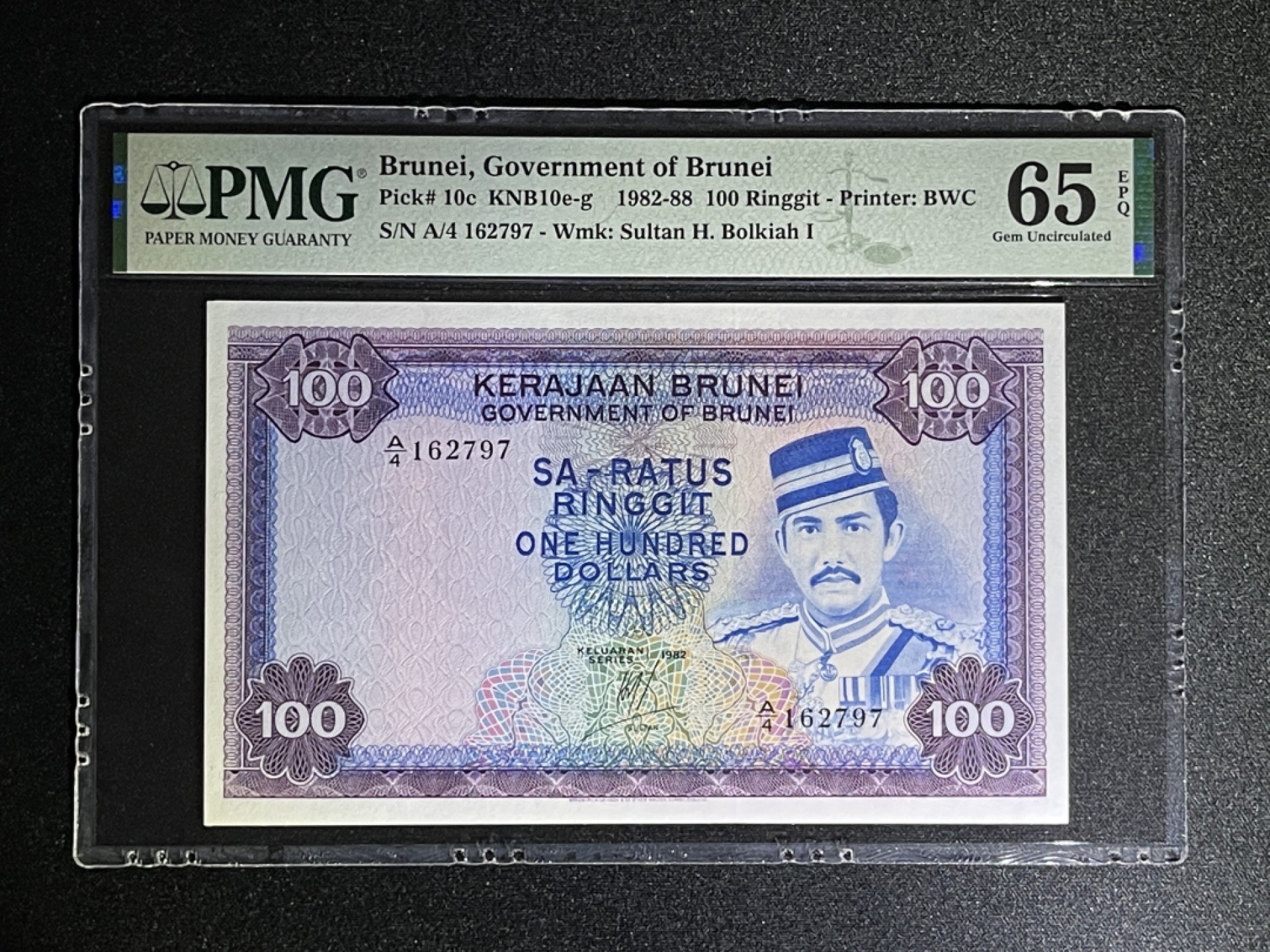 《张总收藏》55期——外币靓号 文莱100镑 PMG65E 1982年 A4冠 文莱第二十九任苏丹博尔基亚
