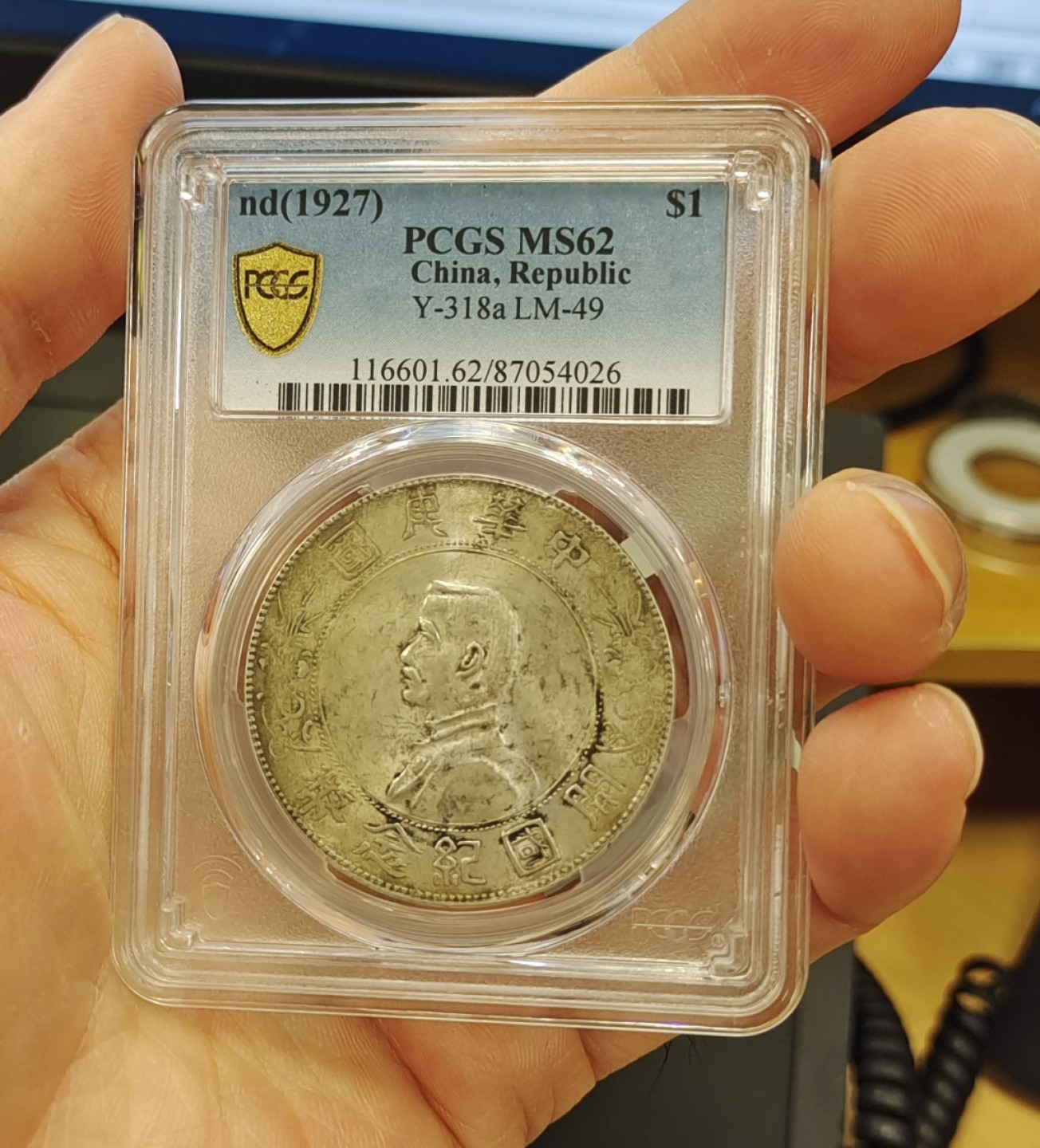 【华誉王者】1998期拍卖 浓黄金彩转轮光老包浆孙像开国纪念币PCGS62分，正常办公室光灯下手机照片直出无后期美化加工，正反面都是深色浓厚黄金彩，前后转轮光，带老包浆，编码87054026。
