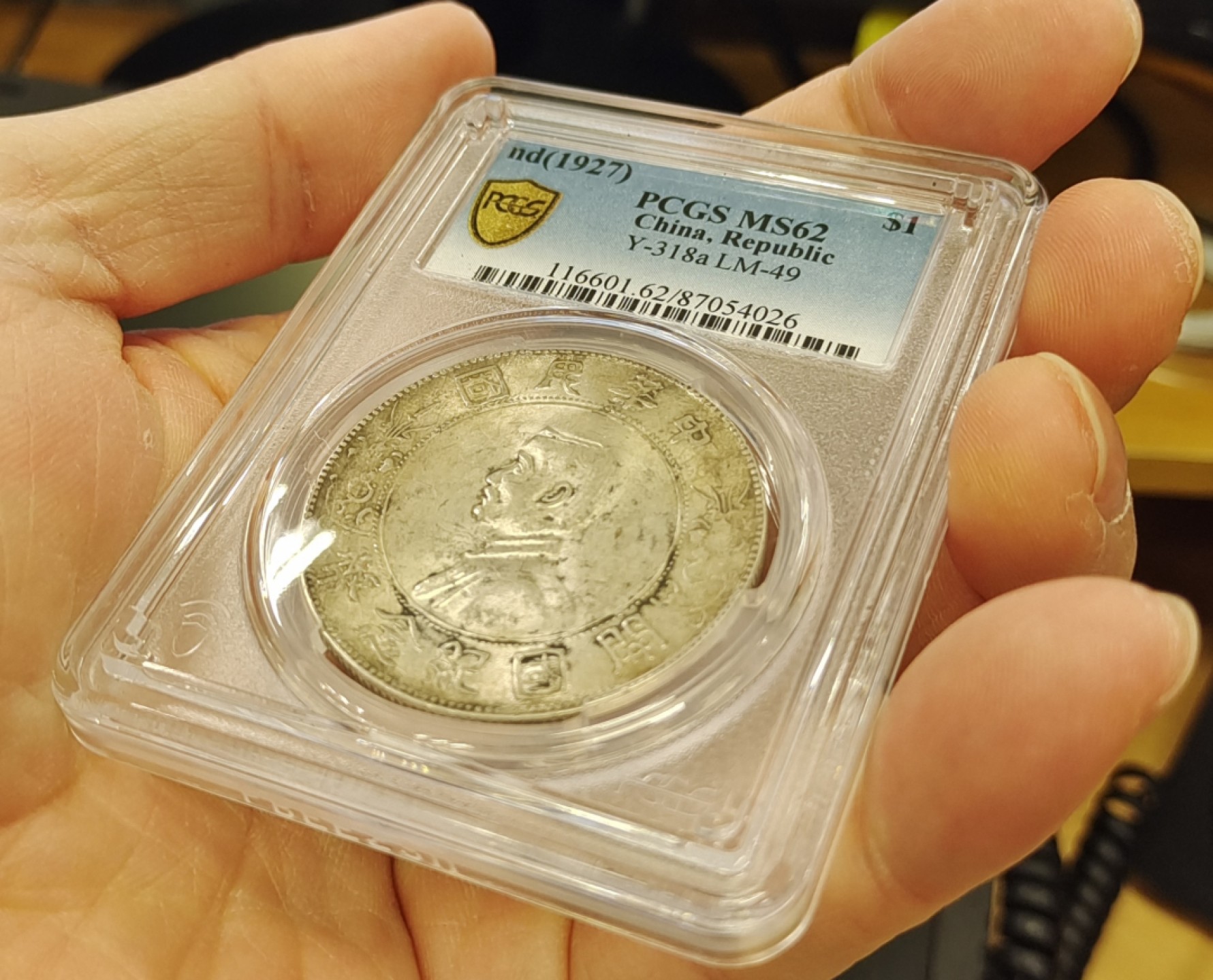 【华誉王者】1998期拍卖 浓黄金彩转轮光老包浆孙像开国纪念币PCGS62分，正常办公室光灯下手机照片直出无后期美化加工，正反面都是深色浓厚黄金彩，前后转轮光，带老包浆，编码87054026。