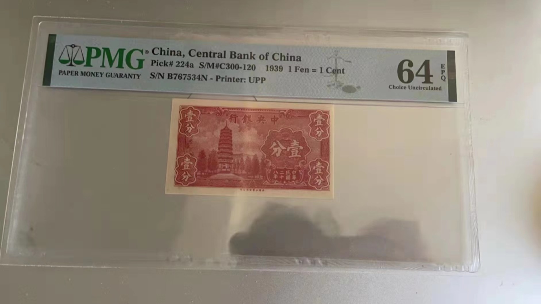 【华誉王者】2010期拍卖 民国纸币中央银行一分pmg，烈士塔一分民国28年中央银行一分纸币，前后字轨，非常袖珍的红一分。颜值，数量都稀少，居中不好，64e移位趣味币一对。B767535N