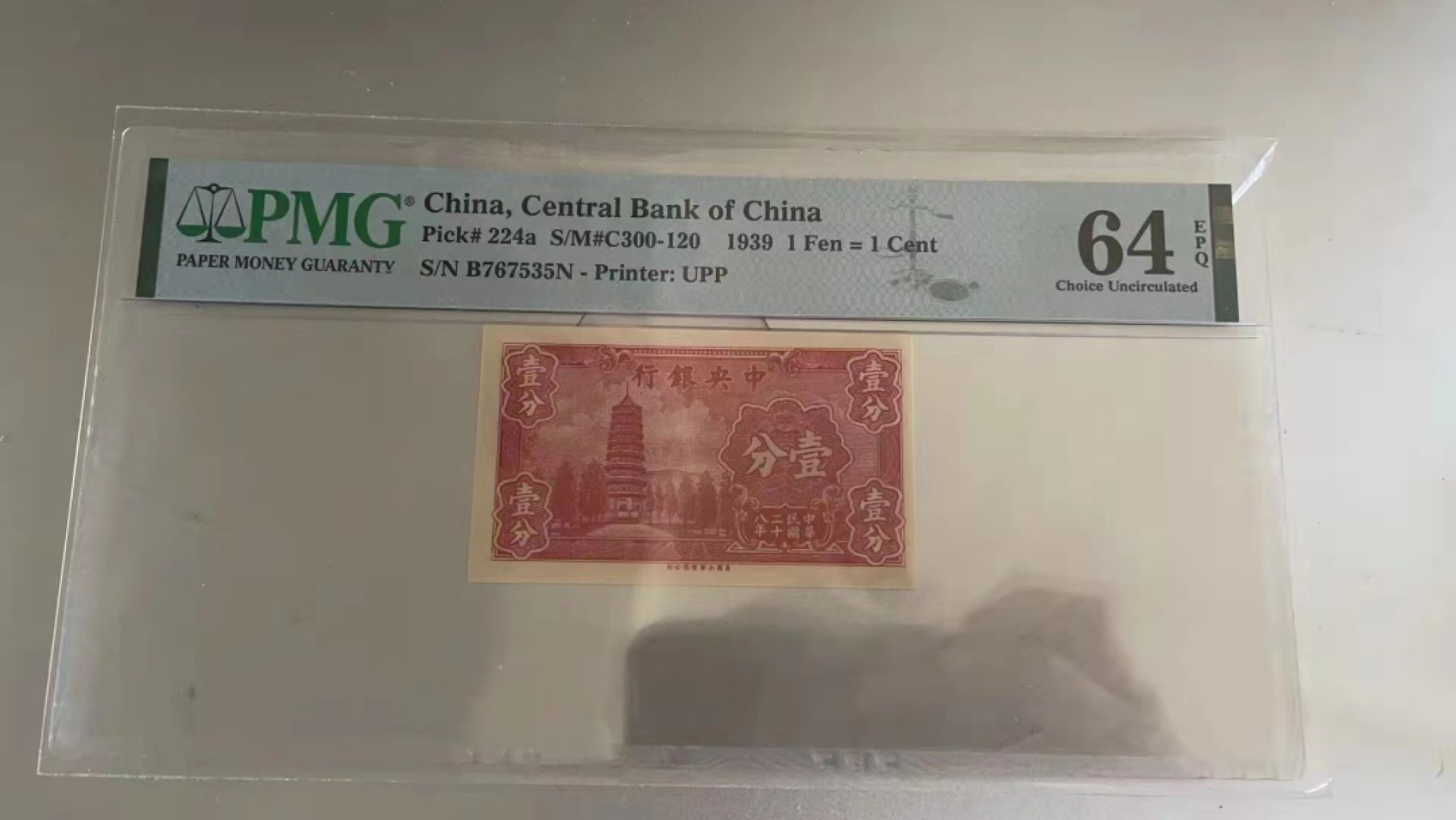 【华誉王者】2010期拍卖 民国纸币中央银行一分pmg，烈士塔一分民国28年中央银行一分纸币，前后字轨，非常袖珍的红一分。颜值，数量都稀少，居中不好，64e移位趣味币一对。B767535N