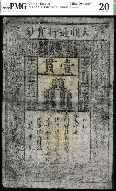 大明洪武年间（1368-1399年）大明通行宝钞壹贯，PMG20NET,Repaired,Corner Added。此券虽有污渍，印章也有被氧化的痕迹，但花纹清晰，气韵古朴，引人注目的巨大票幅，记录着当年明月的历史痕迹！