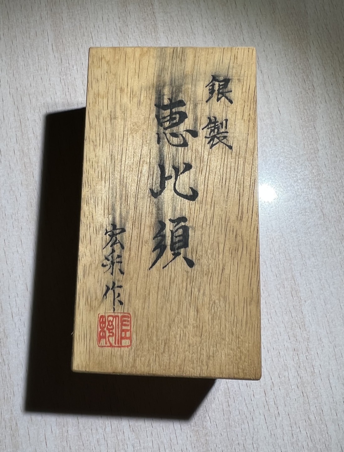 大猫徽章拍卖第205期 纯银财神惠比须摆件，附原木盒，证书 惠比须（亦称惠比寿、夷，日语：えびす）是日本神话中的海神，属于七福神之一，也是七福神中唯一一个日本固有神明。常见的形象是头戴乌帽子、身穿狩衣、右手持钓竿、左手抱鲷鱼的姿态。惠比须是原先是日本渔民信仰的海上守护神，后来由于海运的兴起而成了商业神、财神，到14、15世纪演变为了全日本民众信仰的财神、商业神。日本著名金工，佐野宏行，号宏采，制作。