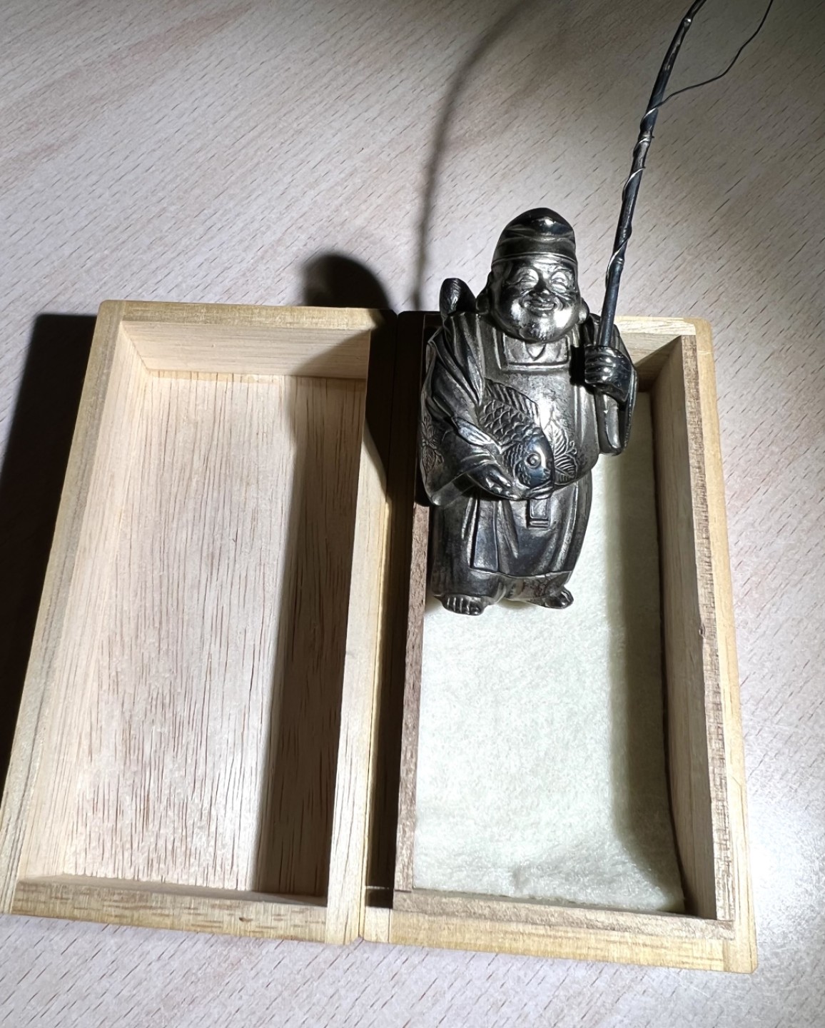 大猫徽章拍卖第205期 纯银财神惠比须摆件，附原木盒，证书 惠比须（亦称惠比寿、夷，日语：えびす）是日本神话中的海神，属于七福神之一，也是七福神中唯一一个日本固有神明。常见的形象是头戴乌帽子、身穿狩衣、右手持钓竿、左手抱鲷鱼的姿态。惠比须是原先是日本渔民信仰的海上守护神，后来由于海运的兴起而成了商业神、财神，到14、15世纪演变为了全日本民众信仰的财神、商业神。日本著名金工，佐野宏行，号宏采，制作。