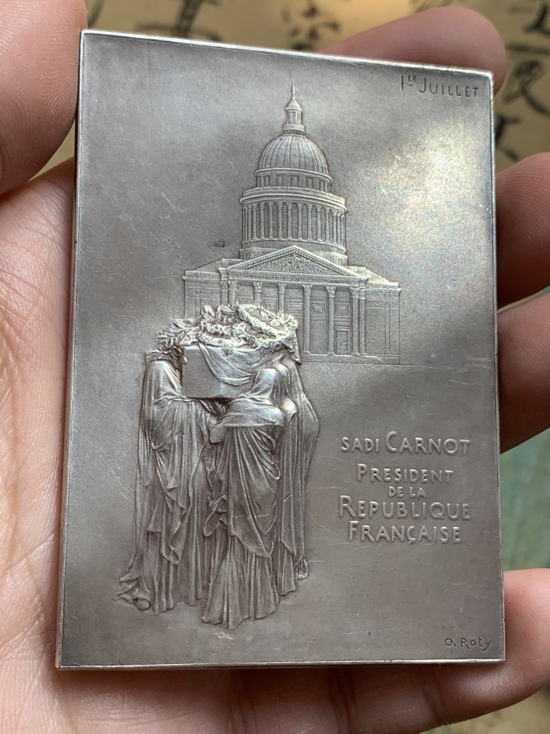 《竞宝斋》第108场-周日，周一 ，周四3场连拍（全场包邮） 法国 1894年卡诺总统葬礼纪念镀银大铜章，带原盒。雕刻大师罗蒂（O Roty）名作，直径80mm*57mm。正面图案为玛丽安娜女神站立于花环簇拥的总统遗体旁，背面一群身穿长袍黑纱的人将棺椁抬向先贤祠