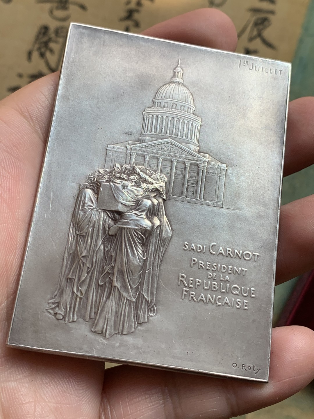 《竞宝斋》第108场-周日，周一 ，周四3场连拍（全场包邮） 法国 1894年卡诺总统葬礼纪念镀银大铜章，带原盒。雕刻大师罗蒂（O Roty）名作，直径80mm*57mm。正面图案为玛丽安娜女神站立于花环簇拥的总统遗体旁，背面一群身穿长袍黑纱的人将棺椁抬向先贤祠