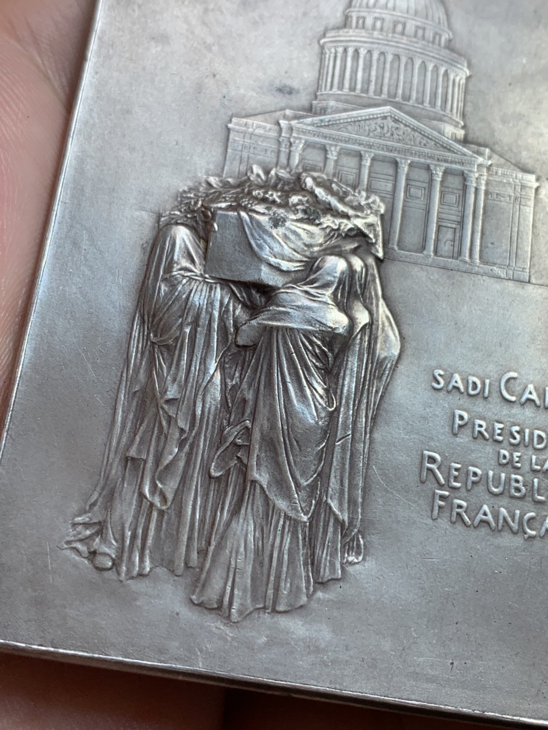 《竞宝斋》第108场-周日，周一 ，周四3场连拍（全场包邮） 法国 1894年卡诺总统葬礼纪念镀银大铜章，带原盒。雕刻大师罗蒂（O Roty）名作，直径80mm*57mm。正面图案为玛丽安娜女神站立于花环簇拥的总统遗体旁，背面一群身穿长袍黑纱的人将棺椁抬向先贤祠