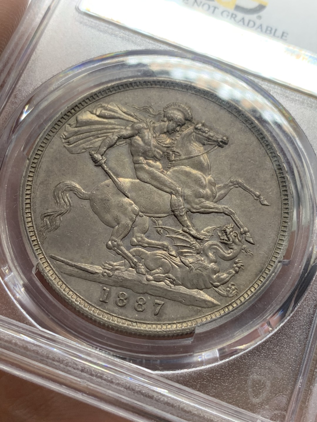 《竞宝斋》第111场-周日，周一 ，2场连拍（全场包邮） PCGS AU好品 英国1887年维多利亚高冠马剑一克朗银币背面非常好正面脸上一个小划痕 适为包浆磨损