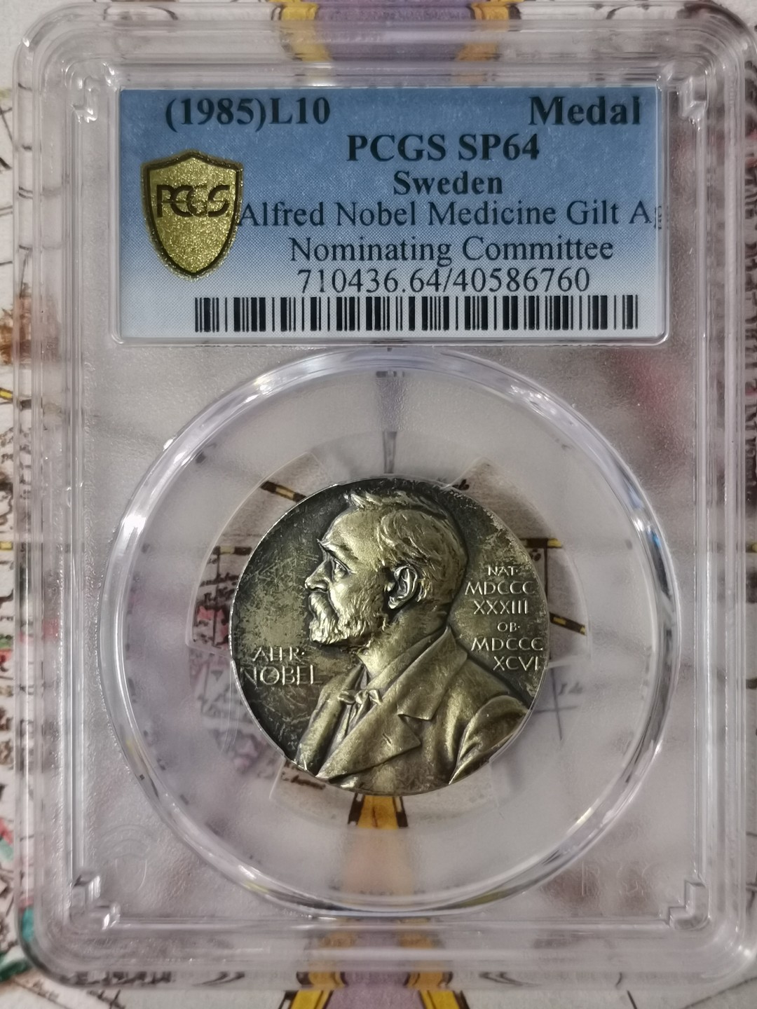 橡树集藏-006场 海纳百川 PCGS-SP64 1985年诺贝尔医学奖镀金银样章，瑞典皇家造币厂铸造，诺贝尔提名委员会颁发，真正的历史荣誉品，错过后悔。独一无二的包浆，实物状态极美。亚军分。正面：諾貝爾半身像朝左；反面：INVENTAS VITAM IUVAT EXCOLUISSE PER ARTES （意：獻給推動人類生活進步的偉大發明家）器皿及埃庫拉皮烏斯的蛇形纏繞權杖；花圈於背。深打，有光帶淺金色調包漿。