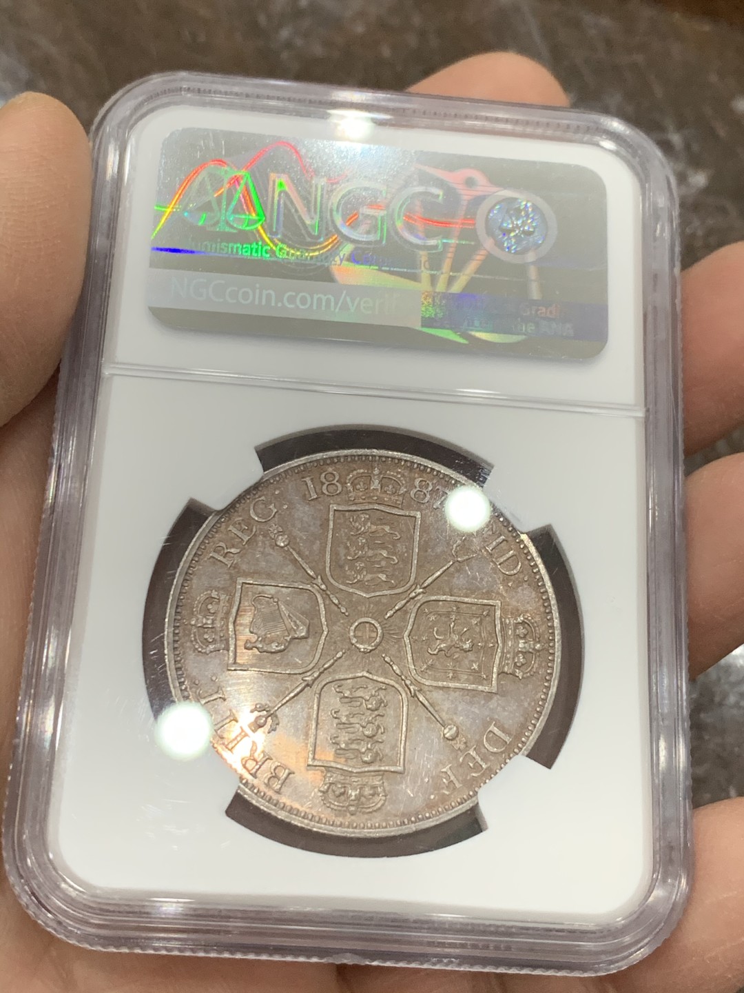 《竞宝斋》第128场-周日，周一 ，2场连拍（全场包邮） NGC-MS63 英国1887年高冠双佛洛林银币，比较少的罗马数字版本，双面呈镜面效果，包浆颜色也是很好看的淡粉彩，上手非常的好看，值得收藏