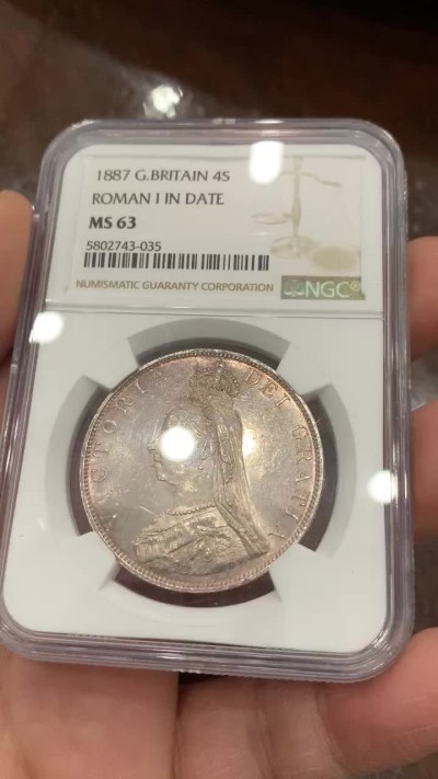 《竞宝斋》第128场-周日，周一 ，2场连拍（全场包邮） NGC-MS63 英国1887年高冠双佛洛林银币，比较少的罗马数字版本，双面呈镜面效果，包浆颜色也是很好看的淡粉彩，上手非常的好看，值得收藏