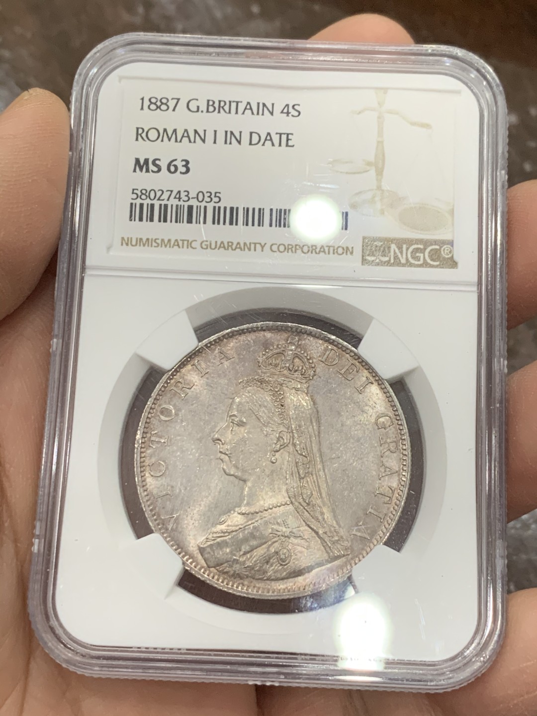 《竞宝斋》第128场-周日，周一 ，2场连拍（全场包邮） NGC-MS63 英国1887年高冠双佛洛林银币，比较少的罗马数字版本，双面呈镜面效果，包浆颜色也是很好看的淡粉彩，上手非常的好看，值得收藏