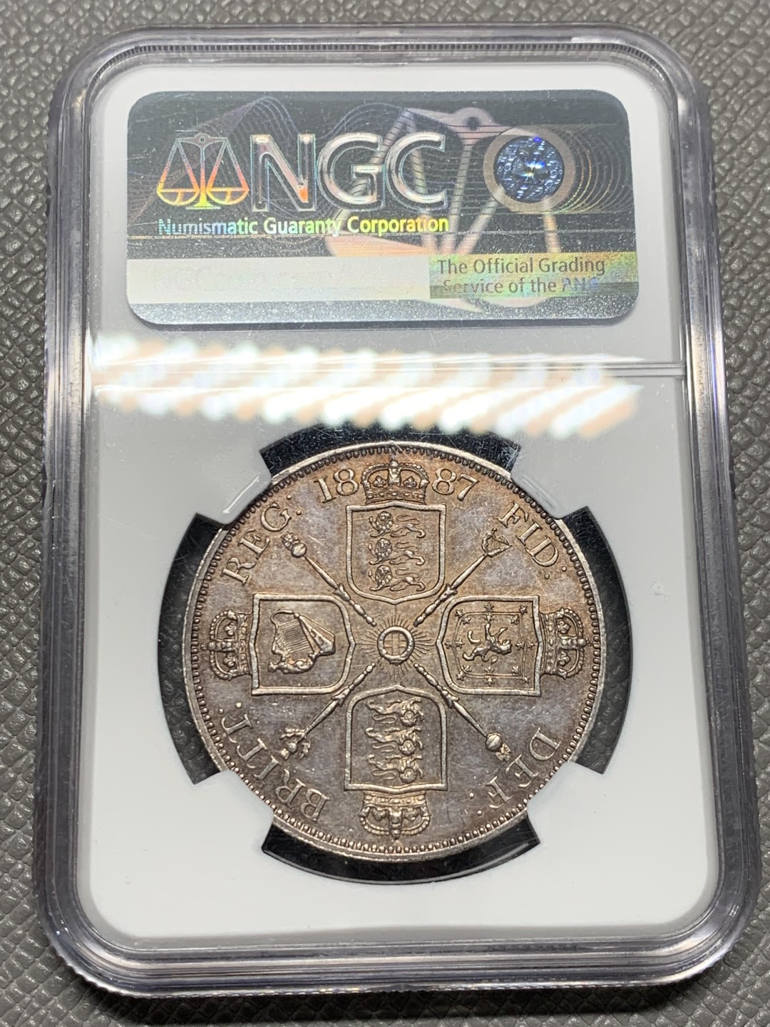 《竞宝斋》第128场-周日，周一 ，2场连拍（全场包邮） NGC-MS63 英国1887年高冠双佛洛林银币，比较少的罗马数字版本，双面呈镜面效果，包浆颜色也是很好看的淡粉彩，上手非常的好看，值得收藏