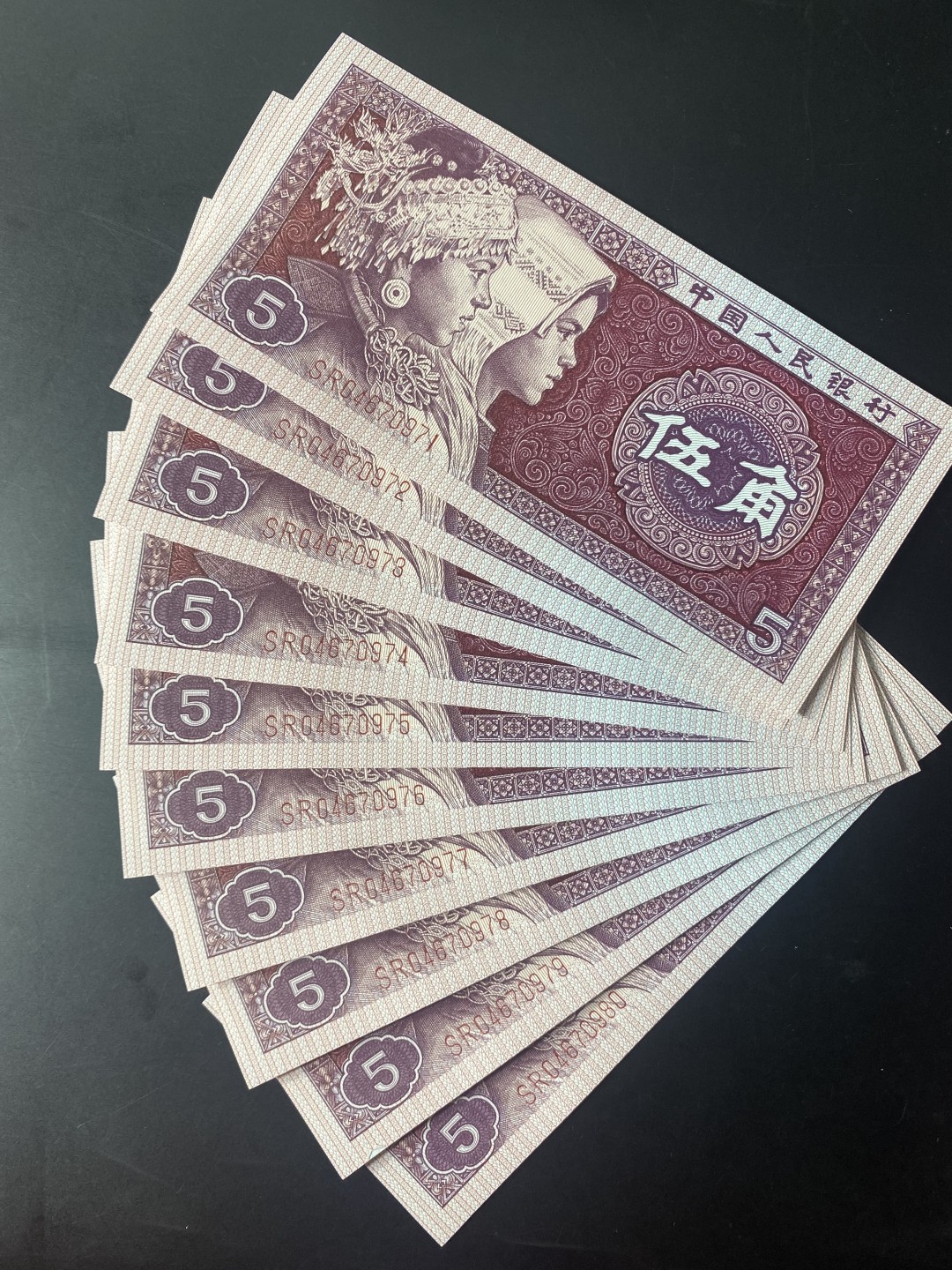 一线荧光币第46期拍场 8005SR至尊如意红，SR04670971_80，裸币标十。至尊红如意的主体颜色呈深枣红色，原本白色的如意纹饰被红色油墨浸染覆盖变成了红色。整个票面油墨厚重油润，凹凸感明显，层次丰富，就像一件浮雕艺术品，显得尊贵典雅，故命名至尊红如意潜力股色差币，一眼清品种