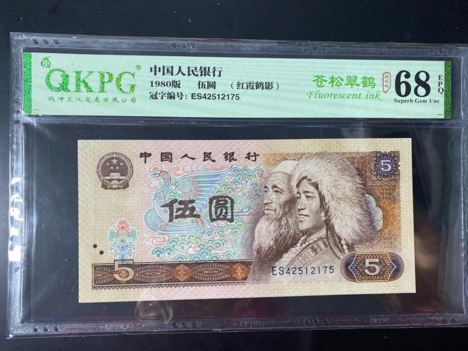 一线荧光币第46期拍场 钱坤评级805ES天王冠苍松翠鹤，ES42512175，评级币单张。苍松翠鹤主要荧光特点为票面正面在365荧光灯下整版为淡黄色网格荧光，松鹤有翠绿色，淡粉色荧光。红霞鹤影主要荧光特点为票面正面在365荧光灯下整版为淡黄色网格荧光，松鹤位置的底纹网格为红色