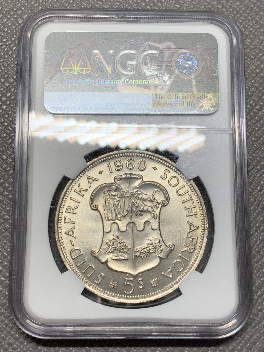 《竞宝斋》第141场-周日，周一 2场 (全场包邮) NGC-MS65 英属南非 1960 南非联盟成立50周年纪念5先令大银币，车轮转光，65难得高分。盒子上有小划，保存无碍