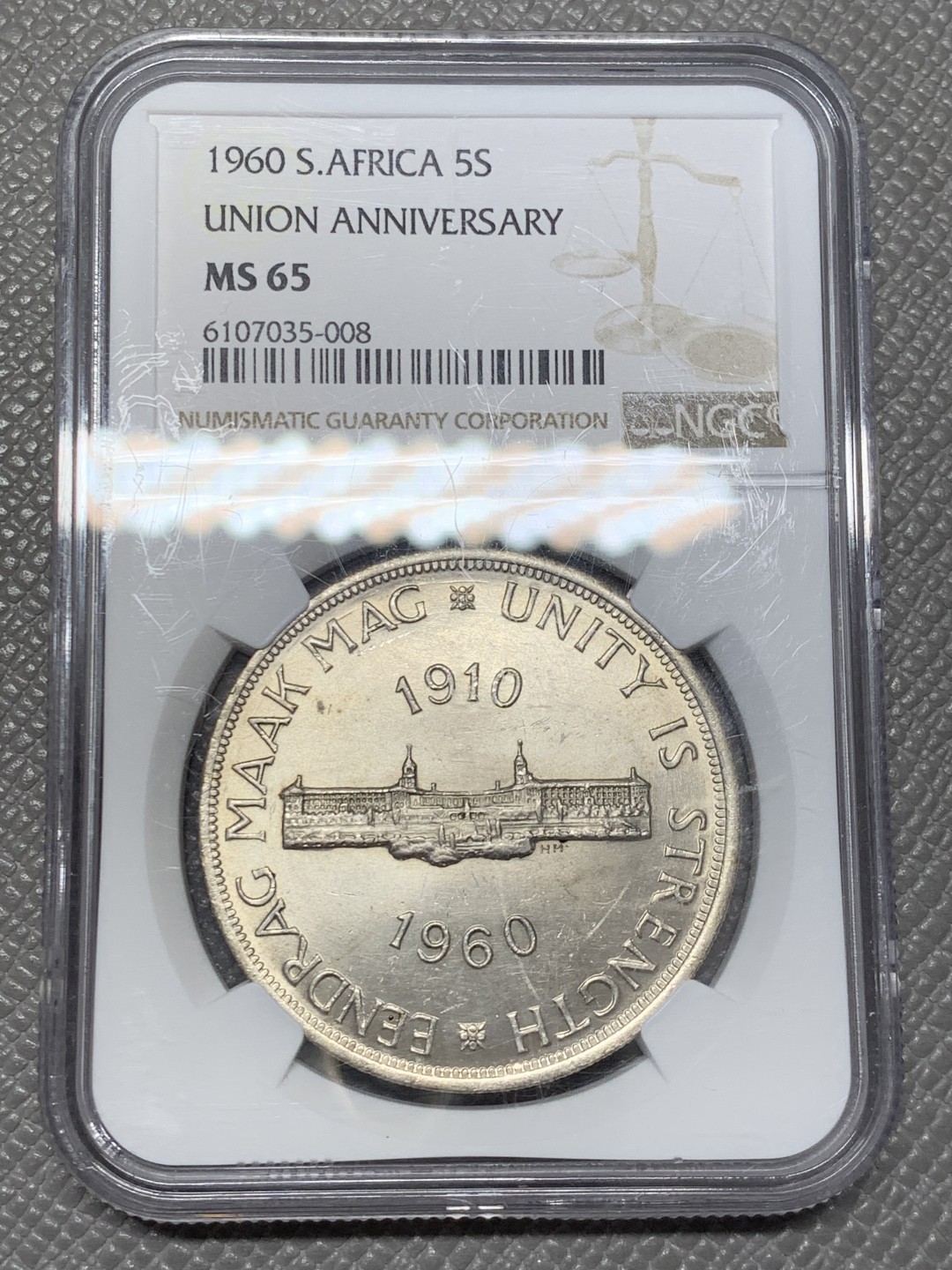 《竞宝斋》第141场-周日，周一 2场 (全场包邮) NGC-MS65 英属南非 1960 南非联盟成立50周年纪念5先令大银币，车轮转光，65难得高分。盒子上有小划，保存无碍