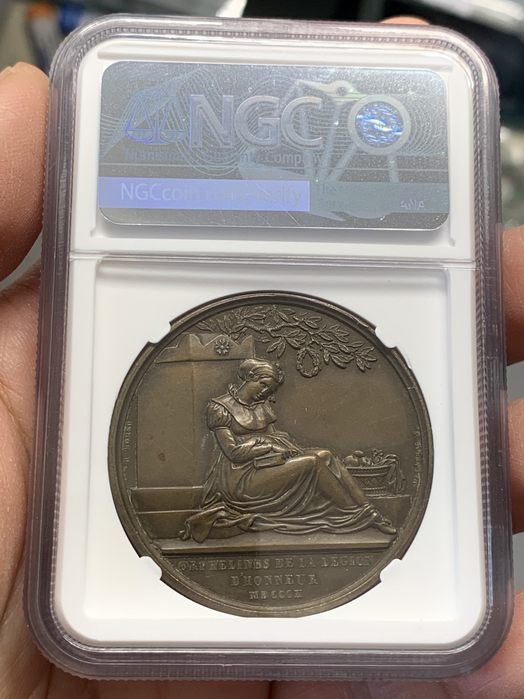 《竞宝斋》第141场-周日，周一 2场 (全场包邮) NGC-MS63BN 唯一亚军分 1810 法国拿破仑一世原铸铜章，设立荣誉军团孤儿教育之家。席地而坐的少女手捧书本，刻画细腻。加厚盒，巧克力包浆