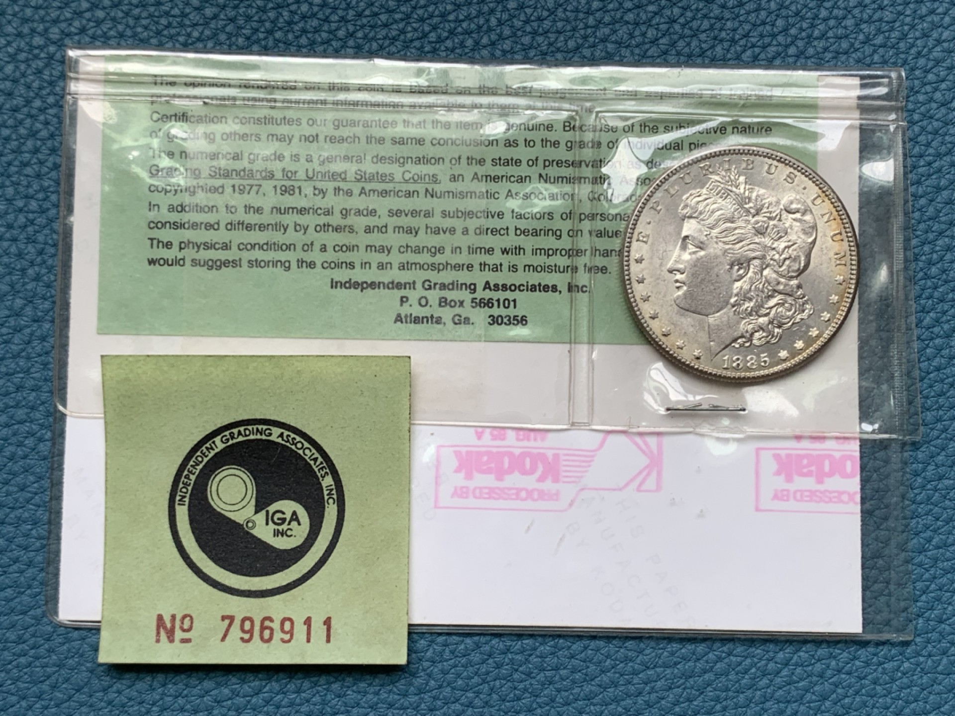 《竞宝斋》三少爷老婆本专场-第156场 (全场包邮) 早期ICG，80年代评级 MS64/65 美国1885年摩根大银币。ICG早期评级的产物，1985年8月27日评级。当时的评级规则是正反面分别评级，正面MS64，反面MS65，附柯达相纸印的币原始照片一张。