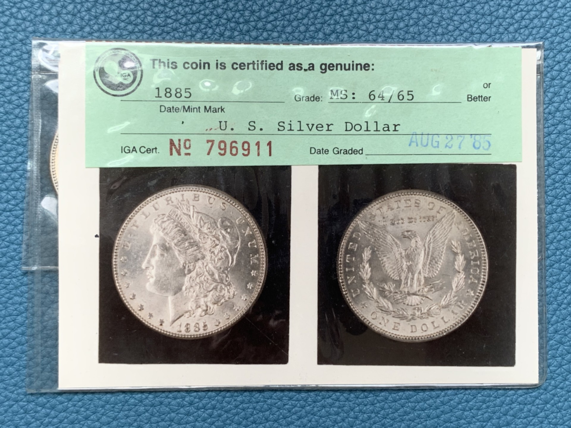 《竞宝斋》三少爷老婆本专场-第156场 (全场包邮) 早期ICG，80年代评级 MS64/65 美国1885年摩根大银币。ICG早期评级的产物，1985年8月27日评级。当时的评级规则是正反面分别评级，正面MS64，反面MS65，附柯达相纸印的币原始照片一张。