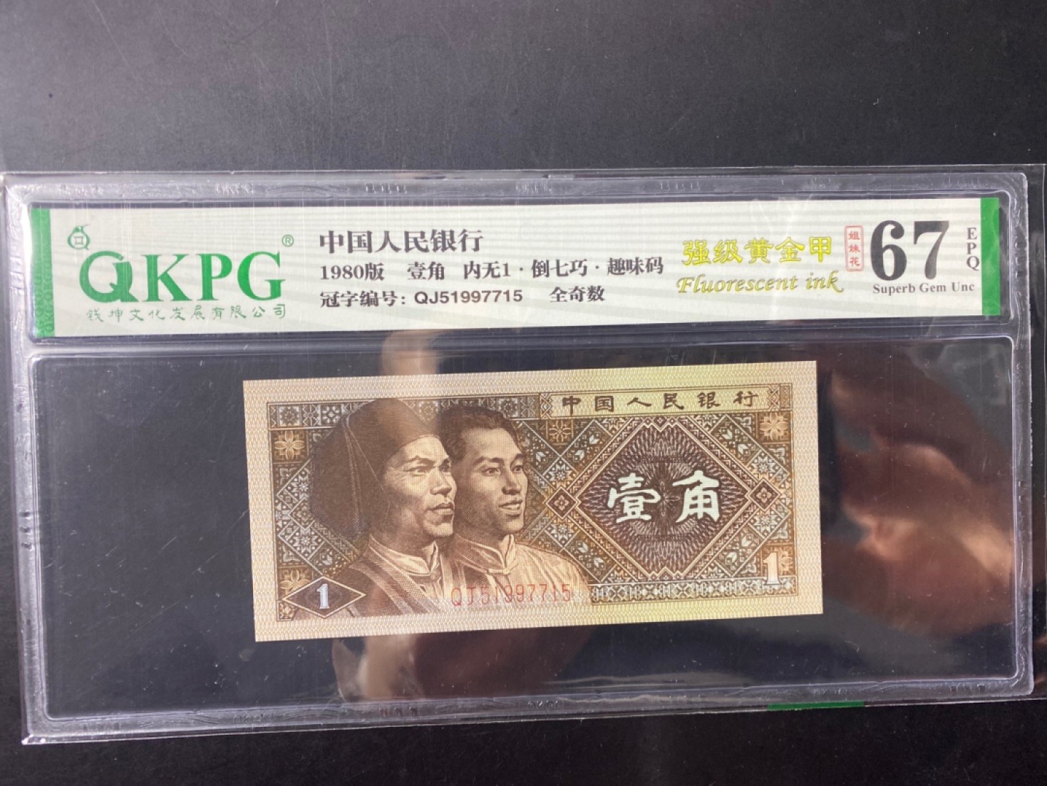 一线荧光币第120期拍场 8001QJ特稀冠强级黄金甲，内无1倒七巧，QJ51997715，全奇数，评级币单张，正常的8001纸币正面左下角与右下角的数字“1”有粗黑的外框，同时里面有一个细细的黑线连接起来的“1”字，类似内、外都是空心的美术字“1”。而藏友们研究发现一种特殊8001纸币，左下角或右下角的数字中空心“1”竟然不见了（或者只留下了一些点或钩），这种钱币就叫做“内无1”，绝品无斑无油。