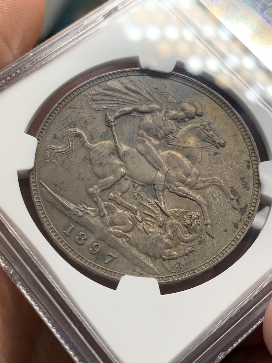 欢迎参加《竞宝斋》五一特拍-第161场-周日，周一 2场 NGC MS62 英国1897年维多利亚披纱马剑1克朗银币，纽曼旧藏重彩包浆