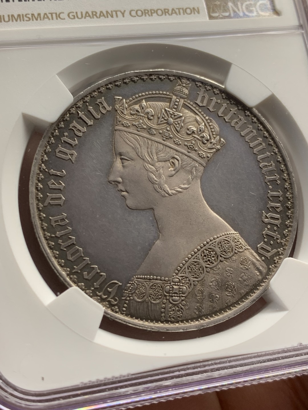 欢迎参加《竞宝斋》五一特拍-第161场-周日，周一 2场 NGC PF62CAMEO 英国 1847年 哥特克朗 大名誉品 带cam的很少 该枚底板镜面效果明显 女王人像中心紫红彩 外围深蓝环彩 背面深蓝环彩 底板干净清爽 无明显拉丝 综合非常棒的一枚哥特克朗