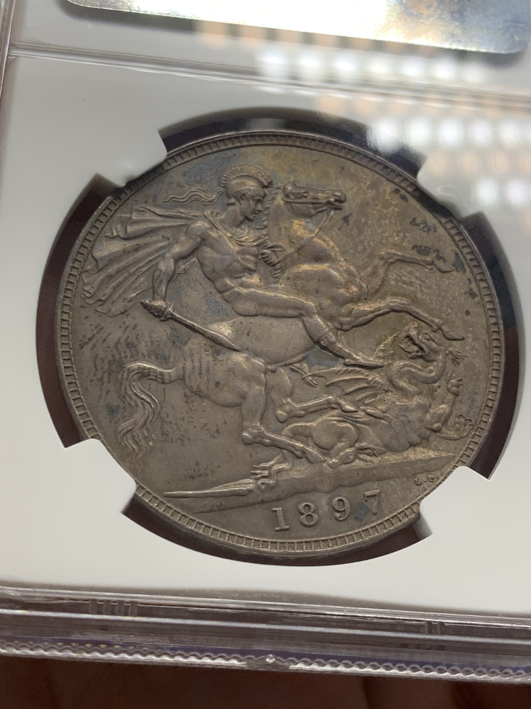 欢迎参加《竞宝斋》五一特拍-第161场-周日，周一 2场 NGC MS62 英国1897年维多利亚披纱马剑1克朗银币，纽曼旧藏重彩包浆