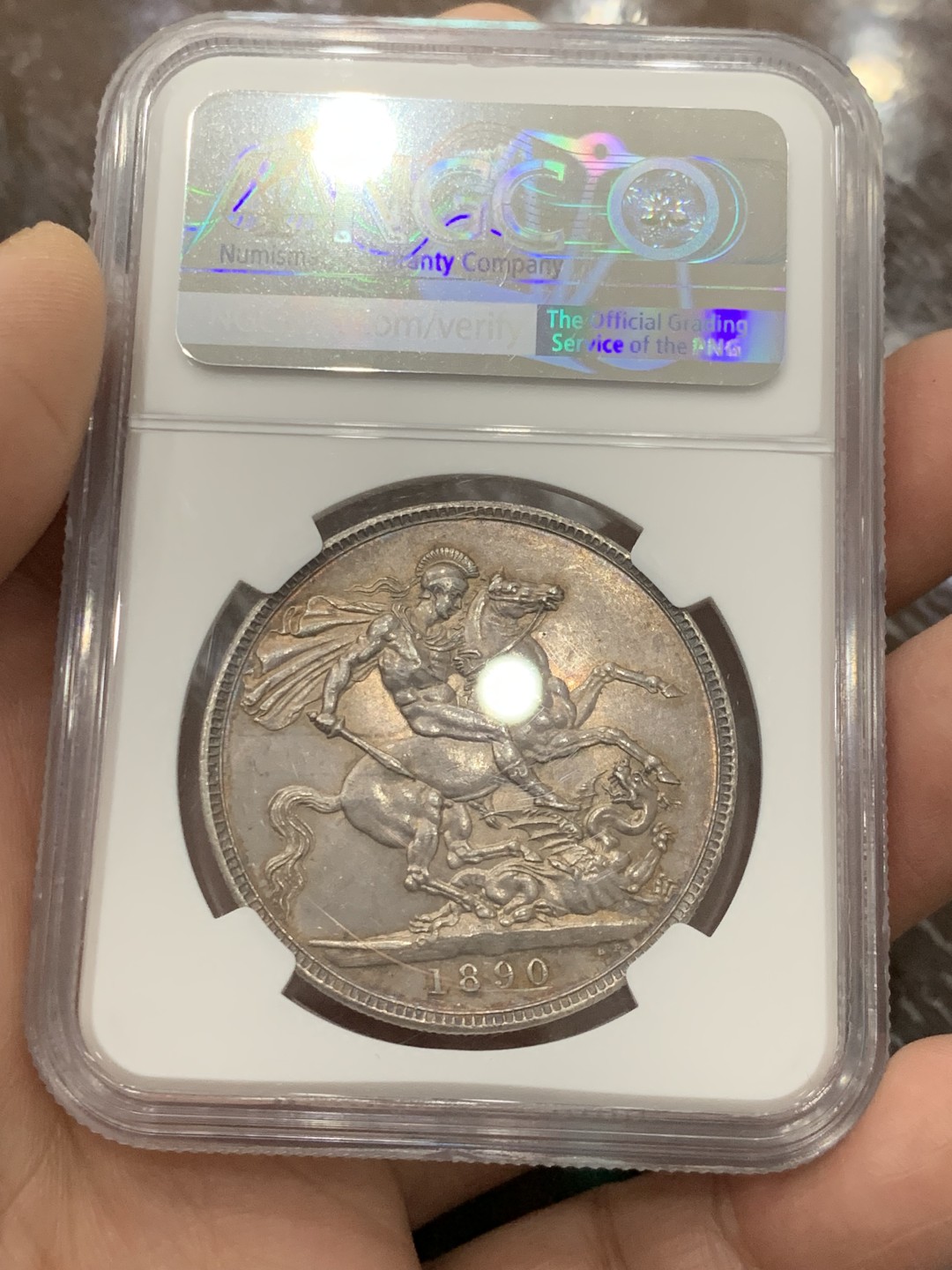 欢迎参加《竞宝斋》五一特拍-第161场-周日，周一 2场 NGC-MS62 英国1890年 1克朗 马剑银币，环彩包浆，较少见年份
