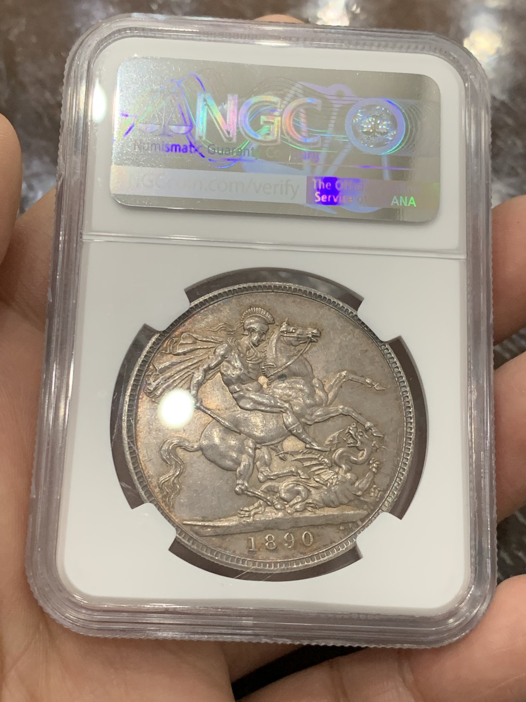 欢迎参加《竞宝斋》五一特拍-第161场-周日，周一 2场 NGC-MS62 英国1890年 1克朗 马剑银币，环彩包浆，较少见年份