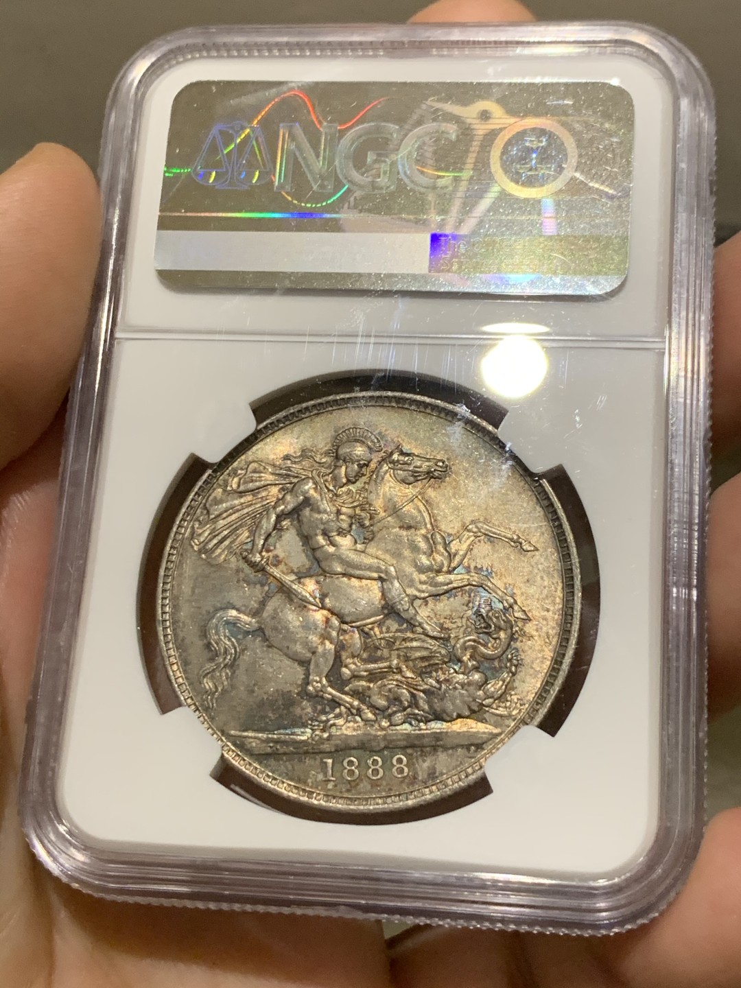 欢迎参加《竞宝斋》五一特拍-第161场-周日，周一 2场 NGC-MS62 英国1888年 1克朗 马剑银币，五彩包浆，盒子略有划痕，不影响密封 稀缺MS