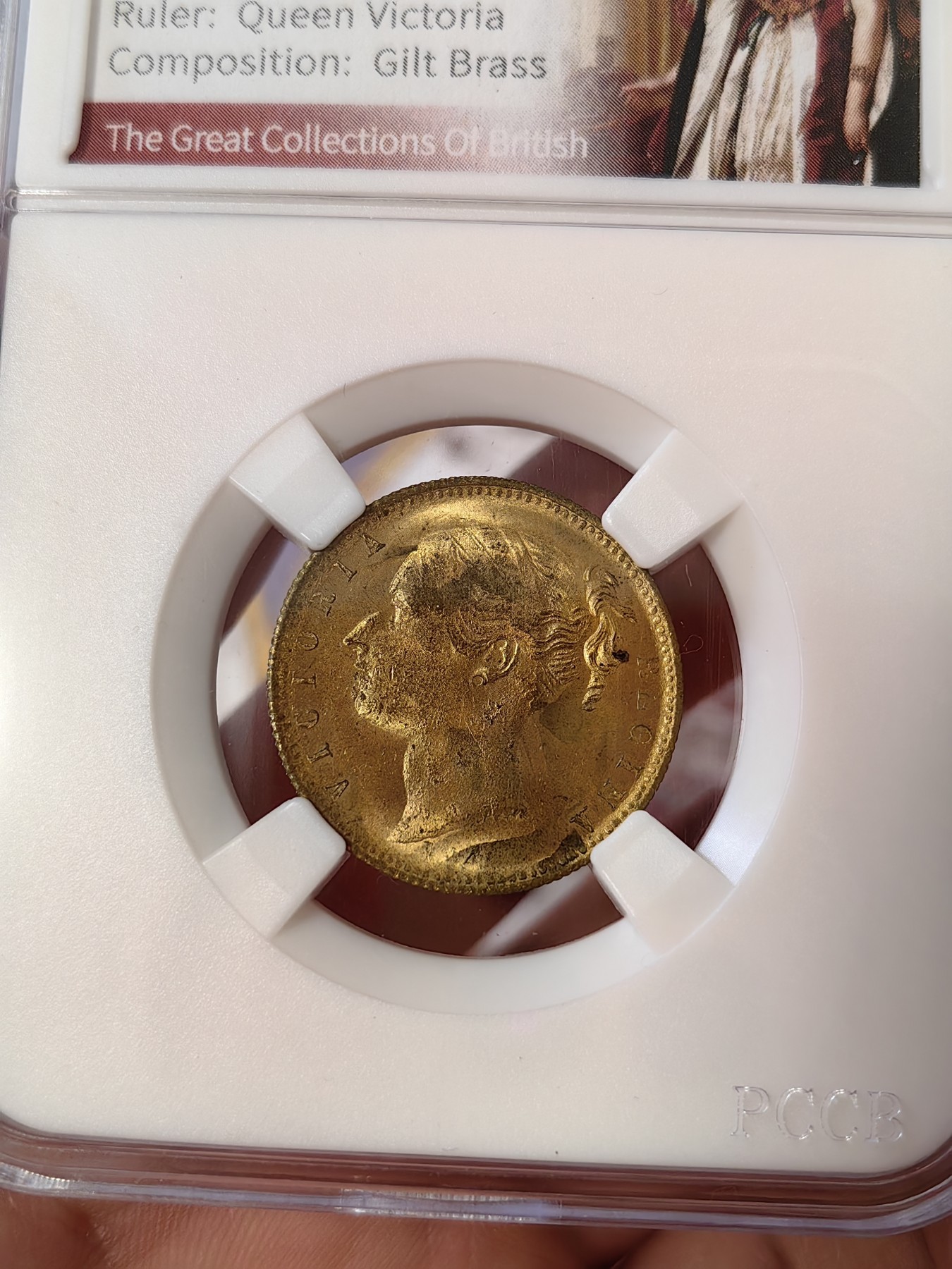 橡树集藏-006场 海纳百川 约1850年 英国 维多利亚女王 惠斯特牌代用币，在牌局中充当计数工具。尺寸参考了索维林的22mm，表面镀金，视觉效果和金镑无二，且少见的出厂状态，工艺比那些汉诺威的token要好上许多许多，雕刻技艺亦可圈可点，亚克力盒为开放式