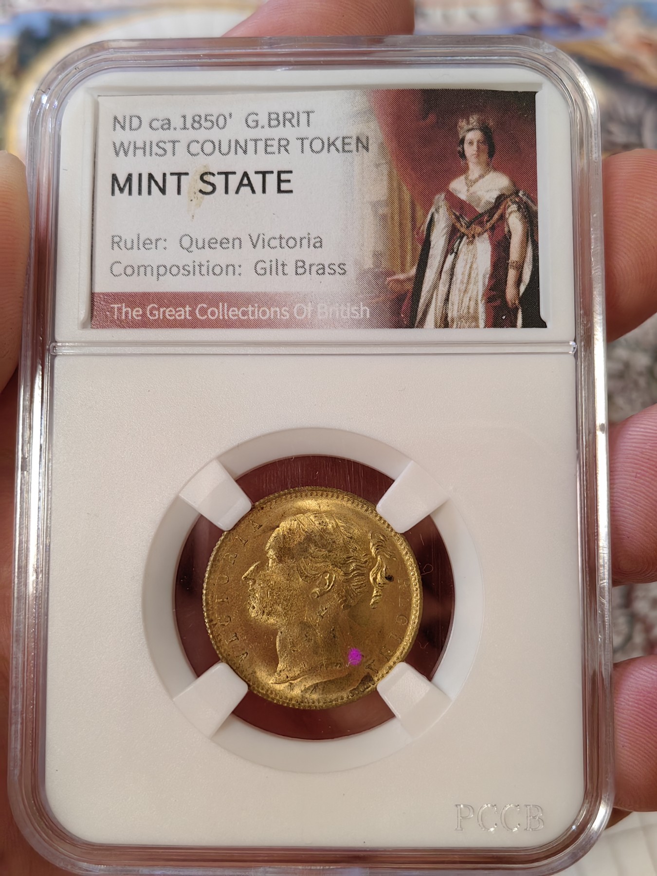 橡树集藏-006场 海纳百川 约1850年 英国 维多利亚女王 惠斯特牌代用币，在牌局中充当计数工具。尺寸参考了索维林的22mm，表面镀金，视觉效果和金镑无二，且少见的出厂状态，工艺比那些汉诺威的token要好上许多许多，雕刻技艺亦可圈可点，亚克力盒为开放式