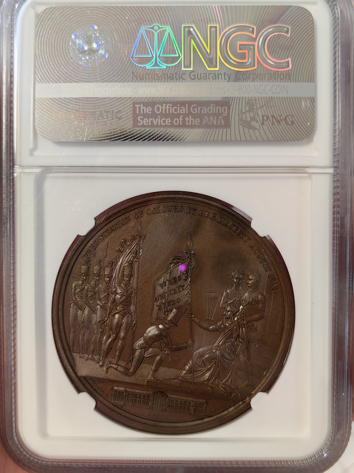 橡树集藏-006场 海纳百川 1813年英国皇室章，乔治三世时期原铸。ngc Ms65，加厚盒。铜色诱人，镜面感十足。背面是女王向皇家近卫军团授予军旗，细节丰富，雕刻精细，超高浮雕。ngc数据库唯一评级，冠军分。军旗上刻字：VIRES ACQUIRT EUNDO。拉丁文，意为“随行聚力”，是古罗马诗人的叙事诗《埃涅阿斯纪》中的一句，意思是“随着传播而越来越有力”。象征着军队听从指挥，雷厉风行。