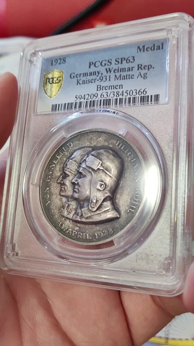 橡树集藏-006场 海纳百川 1928年德国银章，pcgs SP63。纪念不莱梅号飞机飞越大西洋。1928年4月13日，两名德国飞行员驾驶飞机在美国费城着陆，这是人类首次驾驶飞机从大西洋东岸飞到西岸。这两名飞行员在费城受到了盛大欢迎，德国人也以他们为傲，发行 多枚以此事件为主题的纪念章。 双面浓郁包浆，五彩，超高浮雕，实物极美。 人物刻画精细，背面的不莱梅号穿过云雾，飞翔在大西洋上空，海面波光粼粼，惟妙惟肖。