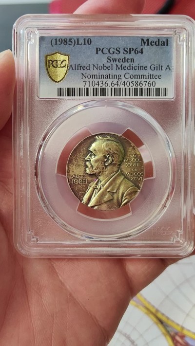 橡树集藏-006场 海纳百川 PCGS-SP64 1985年诺贝尔医学奖镀金银样章，瑞典皇家造币厂铸造，诺贝尔提名委员会颁发，真正的历史荣誉品，错过后悔。独一无二的包浆，实物状态极美。亚军分。正面：諾貝爾半身像朝左；反面：INVENTAS VITAM IUVAT EXCOLUISSE PER ARTES （意：獻給推動人類生活進步的偉大發明家）器皿及埃庫拉皮烏斯的蛇形纏繞權杖；花圈於背。深打，有光帶淺金色調包漿。