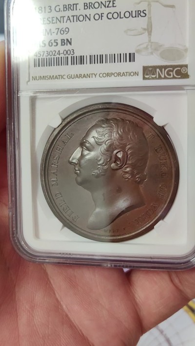 橡树集藏-006场 海纳百川 1813年英国皇室章，乔治三世时期原铸。ngc Ms65，加厚盒。铜色诱人，镜面感十足。背面是女王向皇家近卫军团授予军旗，细节丰富，雕刻精细，超高浮雕。ngc数据库唯一评级，冠军分。军旗上刻字：VIRES ACQUIRT EUNDO。拉丁文，意为“随行聚力”，是古罗马诗人的叙事诗《埃涅阿斯纪》中的一句，意思是“随着传播而越来越有力”。象征着军队听从指挥，雷厉风行。