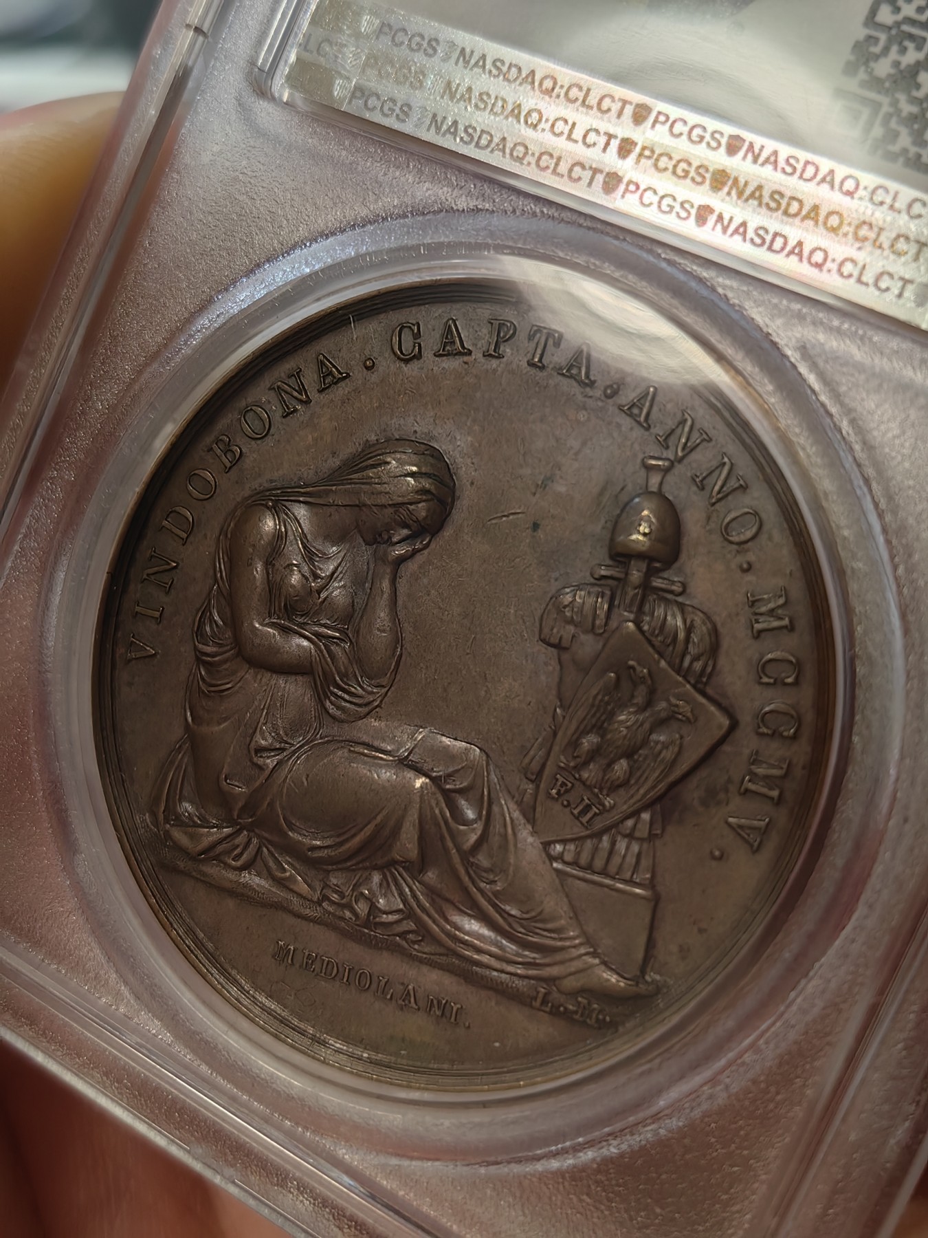 橡树集藏-006场 海纳百川 1805年法国拿破仑一世铜样章，pcgs-SP63。意大利米兰版本。数据库唯一亚军分，少见。攻占维也纳，原铸铜样章，42mm。超高浮雕加厚盒子，状态极佳，实物极美。正面:拿皇头戴月桂冠和柯林斯式头盔装饰有鹰和霹雳，冠饰蛇。背面:奥地利维也纳女神因首都被法军攻占，神情哀伤，有一种征服的快感。法兰西帝国拿破仑大帝的辉煌岁月，横扫欧洲。Vive La France！