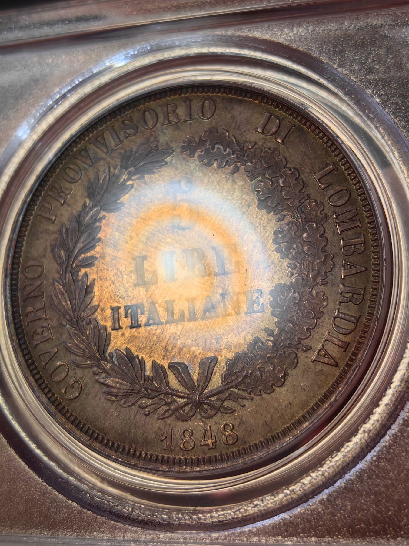 橡树集藏-006场 海纳百川 PCGS MS-64  1848年意大利伦巴第-威尼斯5里拉大银，米兰造币厂。钢灰色的底板呈现出琥珀色和浅洋红色虹彩的痕迹，突出了整个币面。背面有罕见的包浆回声纹，底板几乎没有瑕疵。pc老盒子，品质保证。正面是右手执长矛权杖的加冕自由女神，拉丁铭文:ITALIA LIBERA DIO LO VUOLE，上帝呼唤自由之意大利。女神的左手指向铭文“DIO”,意大利语中上帝的意思，很有深意的经典设计。 