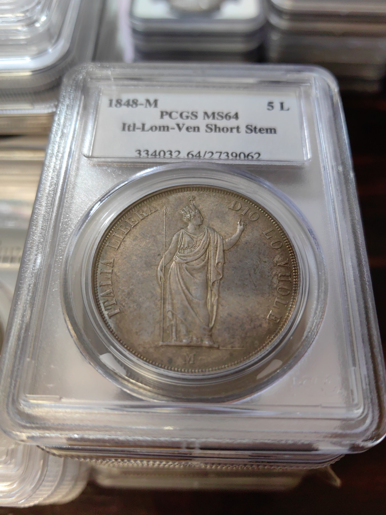 橡树集藏-006场 海纳百川 PCGS MS-64  1848年意大利伦巴第-威尼斯5里拉大银，米兰造币厂。钢灰色的底板呈现出琥珀色和浅洋红色虹彩的痕迹，突出了整个币面。背面有罕见的包浆回声纹，底板几乎没有瑕疵。pc老盒子，品质保证。正面是右手执长矛权杖的加冕自由女神，拉丁铭文:ITALIA LIBERA DIO LO VUOLE，上帝呼唤自由之意大利。女神的左手指向铭文“DIO”,意大利语中上帝的意思，很有深意的经典设计。 