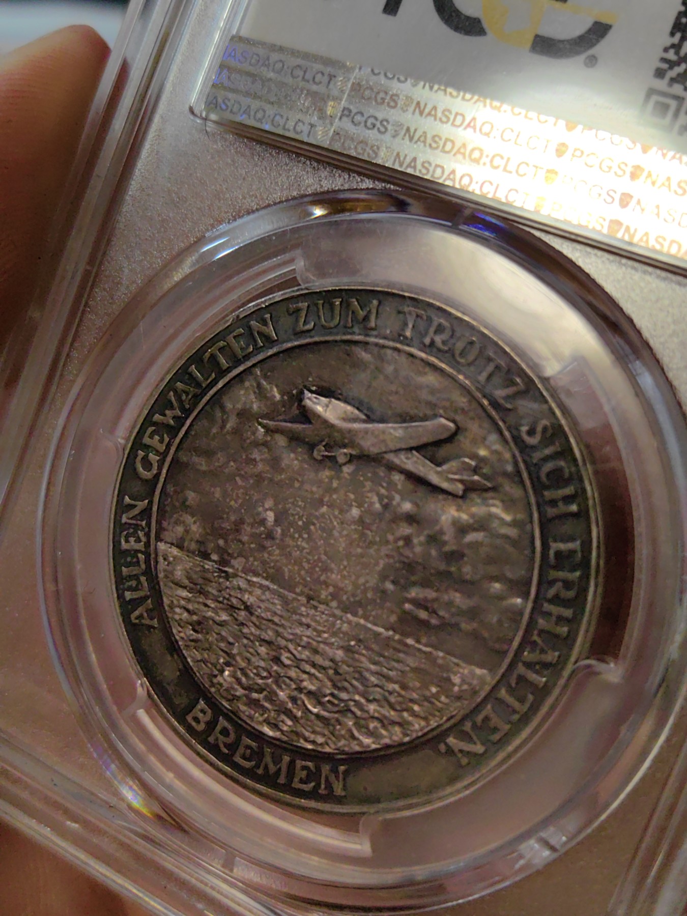 橡树集藏-006场 海纳百川 1928年德国银章，pcgs SP63。纪念不莱梅号飞机飞越大西洋。1928年4月13日，两名德国飞行员驾驶飞机在美国费城着陆，这是人类首次驾驶飞机从大西洋东岸飞到西岸。这两名飞行员在费城受到了盛大欢迎，德国人也以他们为傲，发行 多枚以此事件为主题的纪念章。 双面浓郁包浆，五彩，超高浮雕，实物极美。 人物刻画精细，背面的不莱梅号穿过云雾，飞翔在大西洋上空，海面波光粼粼，惟妙惟肖。