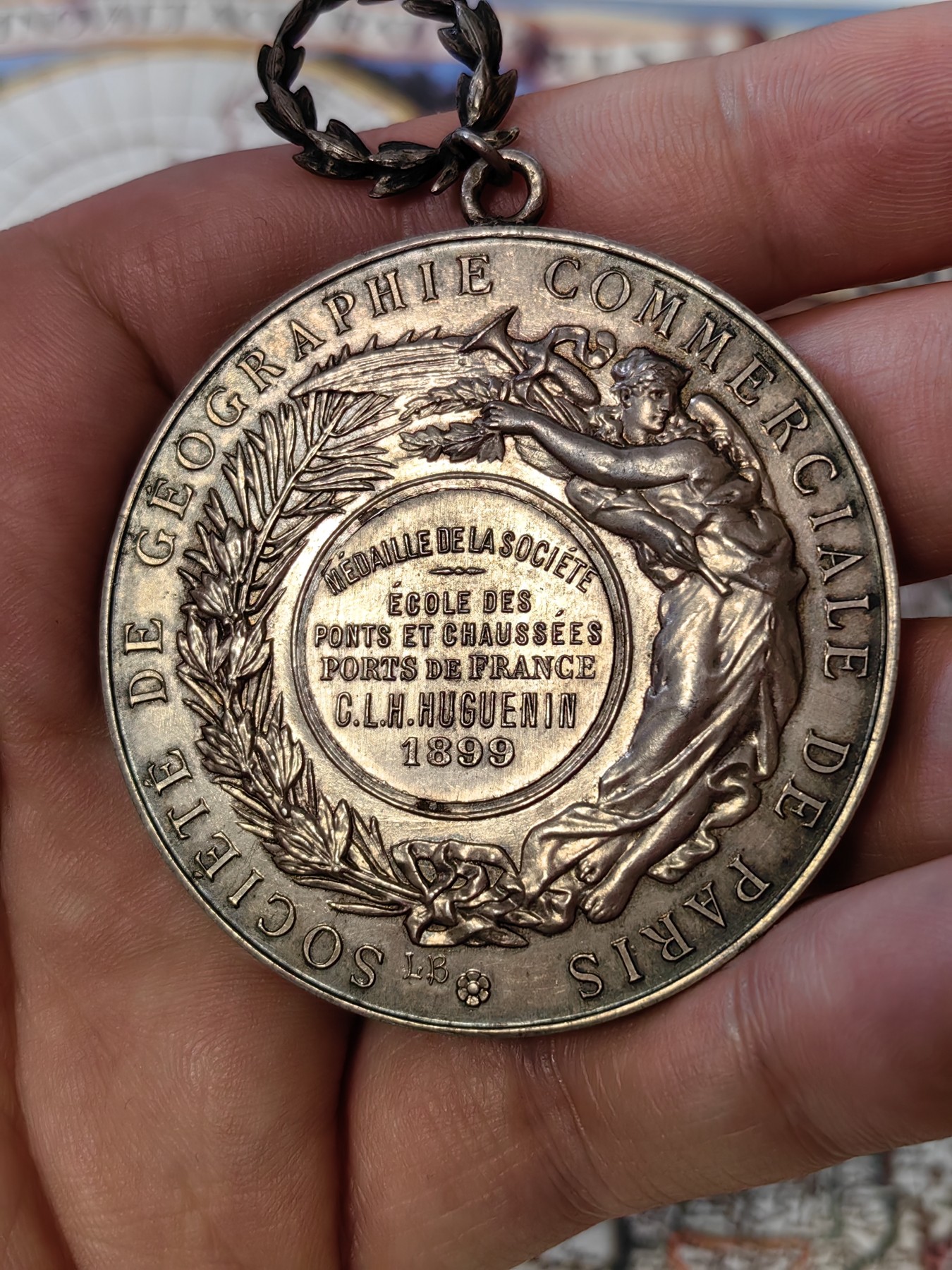 橡树集藏-006场 海纳百川 法国商业地理学会银奖章，1899 年。GEM 未流通。51毫米，58.92 克。作者：L.Botte。1899 年发行并赠送给卡米尔-莱昂-伊波利特·胡格南。正面：地理女神站在左侧，将月桂花环放在商业女神上，手持双杖；背景是商业和工业的标志，例如地球仪、敦、齿轮、铁砧、灯塔和船。完美出厂品相，高浮雕细节极佳，女神和天使柔美动人。