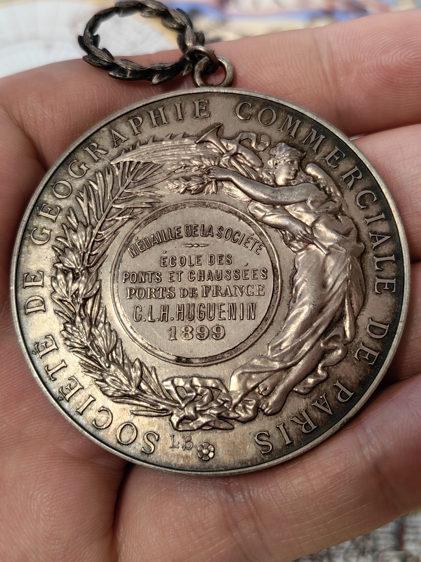 橡树集藏-006场 海纳百川 法国商业地理学会银奖章，1899 年。GEM 未流通。51毫米，58.92 克。作者：L.Botte。1899 年发行并赠送给卡米尔-莱昂-伊波利特·胡格南。正面：地理女神站在左侧，将月桂花环放在商业女神上，手持双杖；背景是商业和工业的标志，例如地球仪、敦、齿轮、铁砧、灯塔和船。完美出厂品相，高浮雕细节极佳，女神和天使柔美动人。