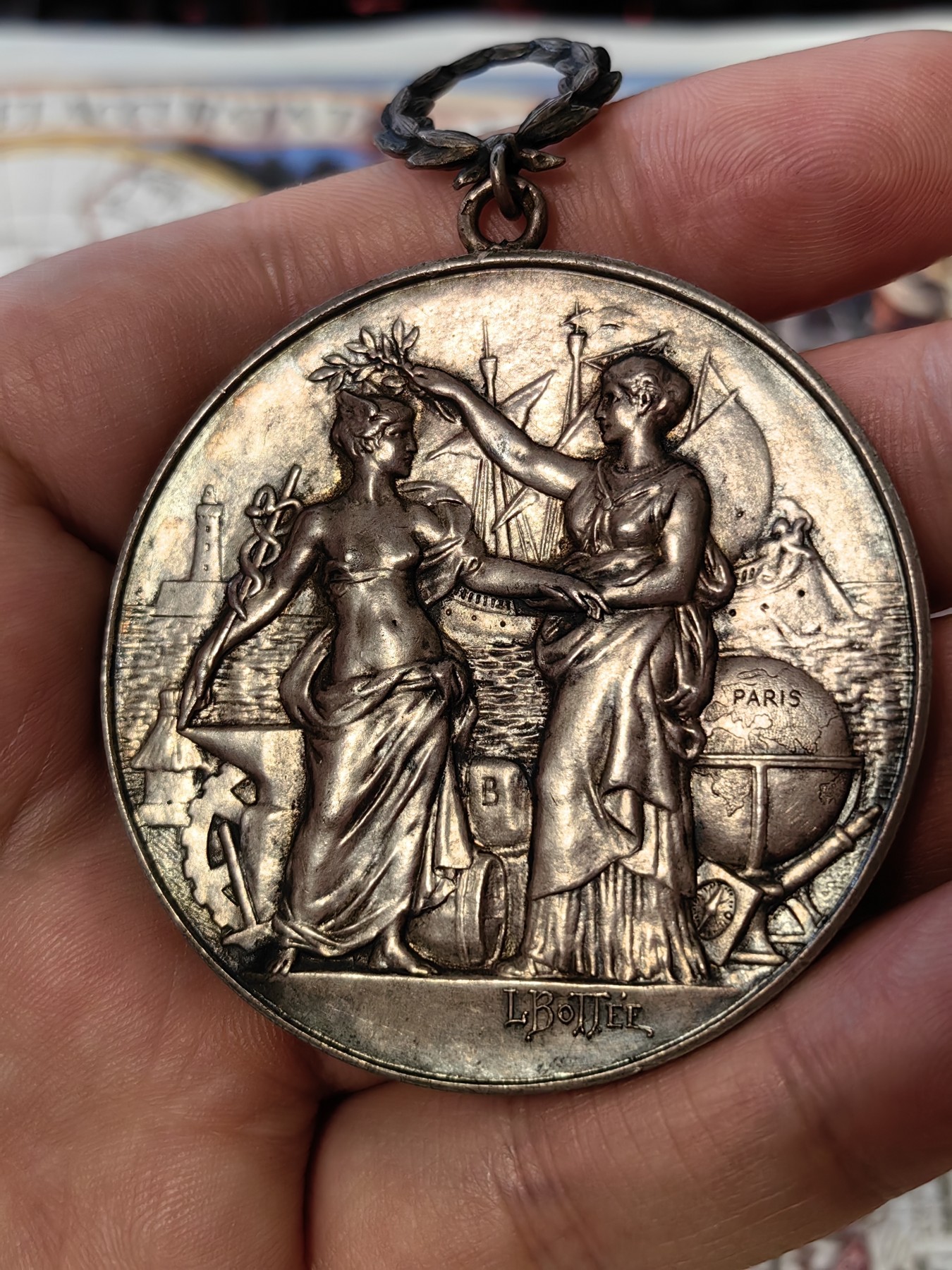 橡树集藏-006场 海纳百川 法国商业地理学会银奖章，1899 年。GEM 未流通。51毫米，58.92 克。作者：L.Botte。1899 年发行并赠送给卡米尔-莱昂-伊波利特·胡格南。正面：地理女神站在左侧，将月桂花环放在商业女神上，手持双杖；背景是商业和工业的标志，例如地球仪、敦、齿轮、铁砧、灯塔和船。完美出厂品相，高浮雕细节极佳，女神和天使柔美动人。