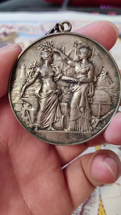 橡树集藏-006场 海纳百川 法国商业地理学会银奖章，1899 年。GEM 未流通。51毫米，58.92 克。作者：L.Botte。1899 年发行并赠送给卡米尔-莱昂-伊波利特·胡格南。正面：地理女神站在左侧，将月桂花环放在商业女神上，手持双杖；背景是商业和工业的标志，例如地球仪、敦、齿轮、铁砧、灯塔和船。完美出厂品相，高浮雕细节极佳，女神和天使柔美动人。