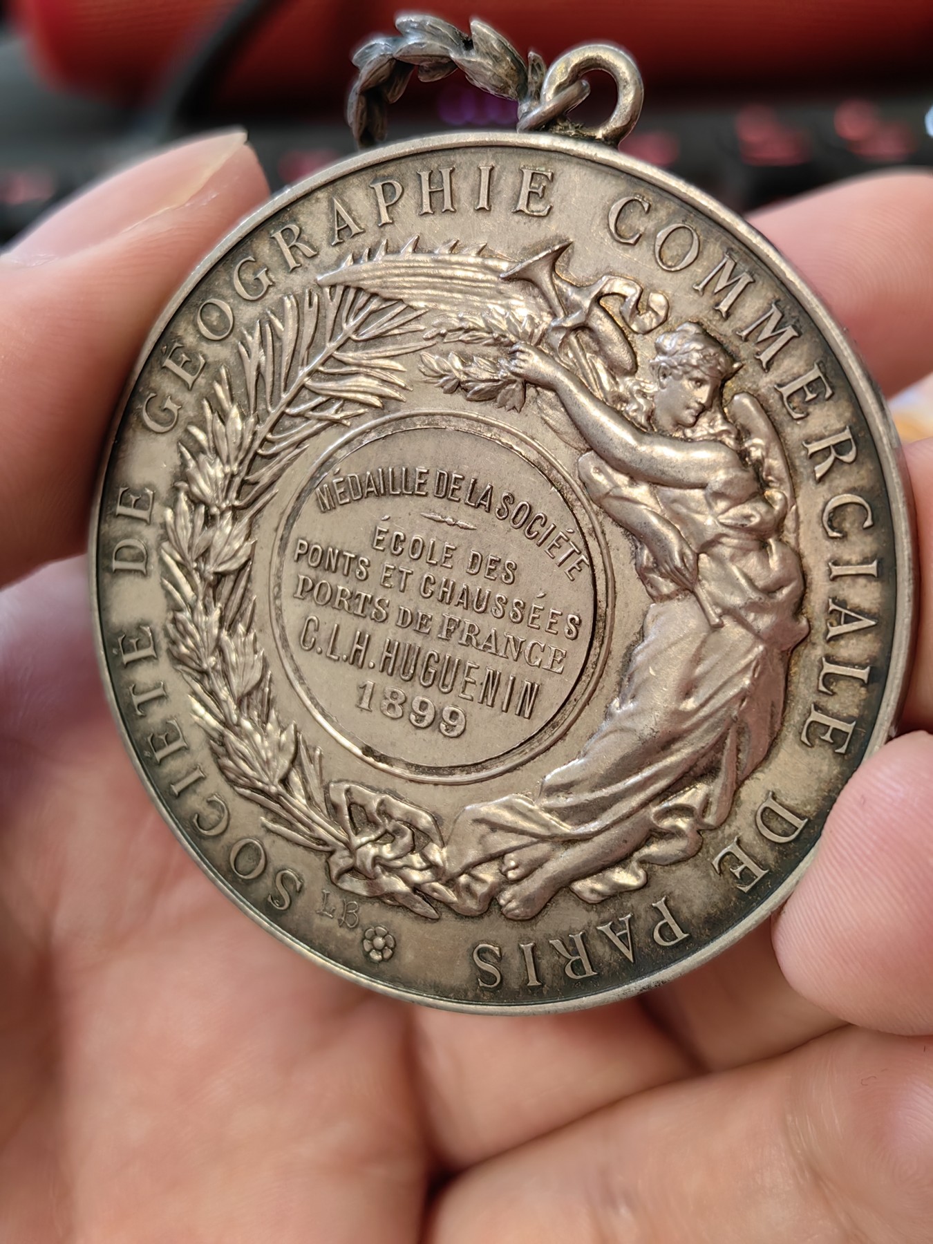 橡树集藏-006场 海纳百川 法国商业地理学会银奖章，1899 年。GEM 未流通。51毫米，58.92 克。作者：L.Botte。1899 年发行并赠送给卡米尔-莱昂-伊波利特·胡格南。正面：地理女神站在左侧，将月桂花环放在商业女神上，手持双杖；背景是商业和工业的标志，例如地球仪、敦、齿轮、铁砧、灯塔和船。完美出厂品相，高浮雕细节极佳，女神和天使柔美动人。